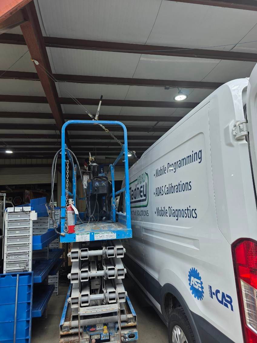 Blue lift beside white moving van inside warehouse loading area