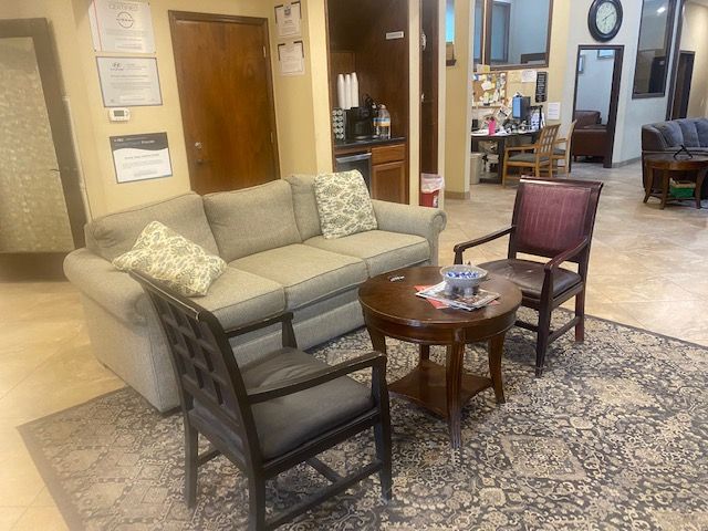 Lobby seating area with beige sofa, two chairs, and a small table on a patterned rug.