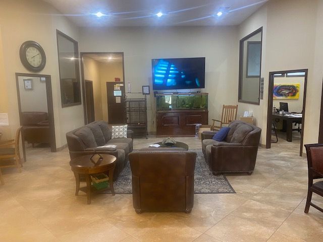 Living room with gray chairs, a TV on a cabinet, and a rug under soft ceiling lights.