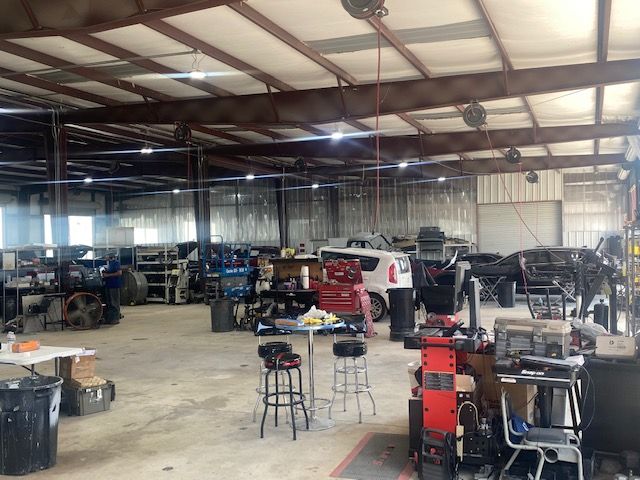 Spacious auto shop with multiple vehicles, tools, and lifts under a metal roof