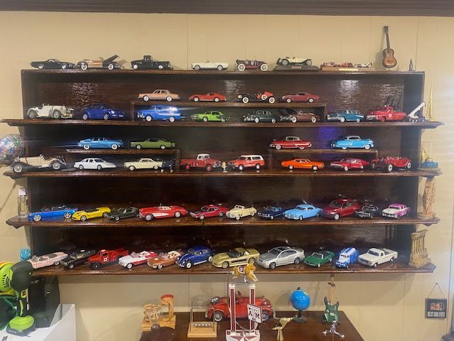 Shelves filled with rows of colorful toy cars displayed on a wall-mounted cabinet