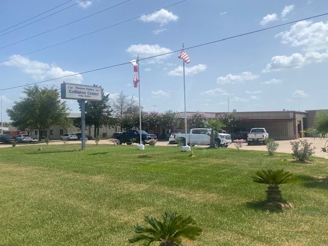 Office building with parking lot, flags, and landscaped lawn under a clear sky