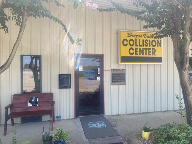 Collision Center storefront with yellow sign, glass door, bench, and wheelchair ramp at the entrance