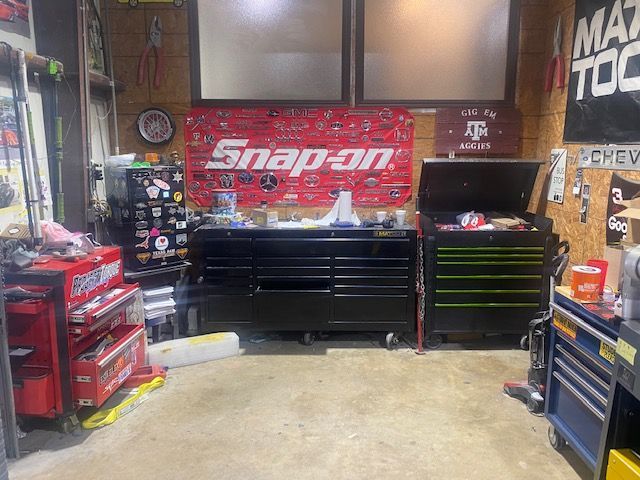 Auto repair shop with red Snap-on toolboxes and a black workbench in the center.