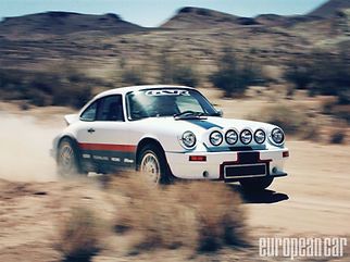 White rally car speeding through a dusty desert landscape, kicking up dirt and blur.