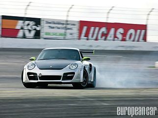 Silver Porsche sports car drifting on a racetrack with smoke trailing behind