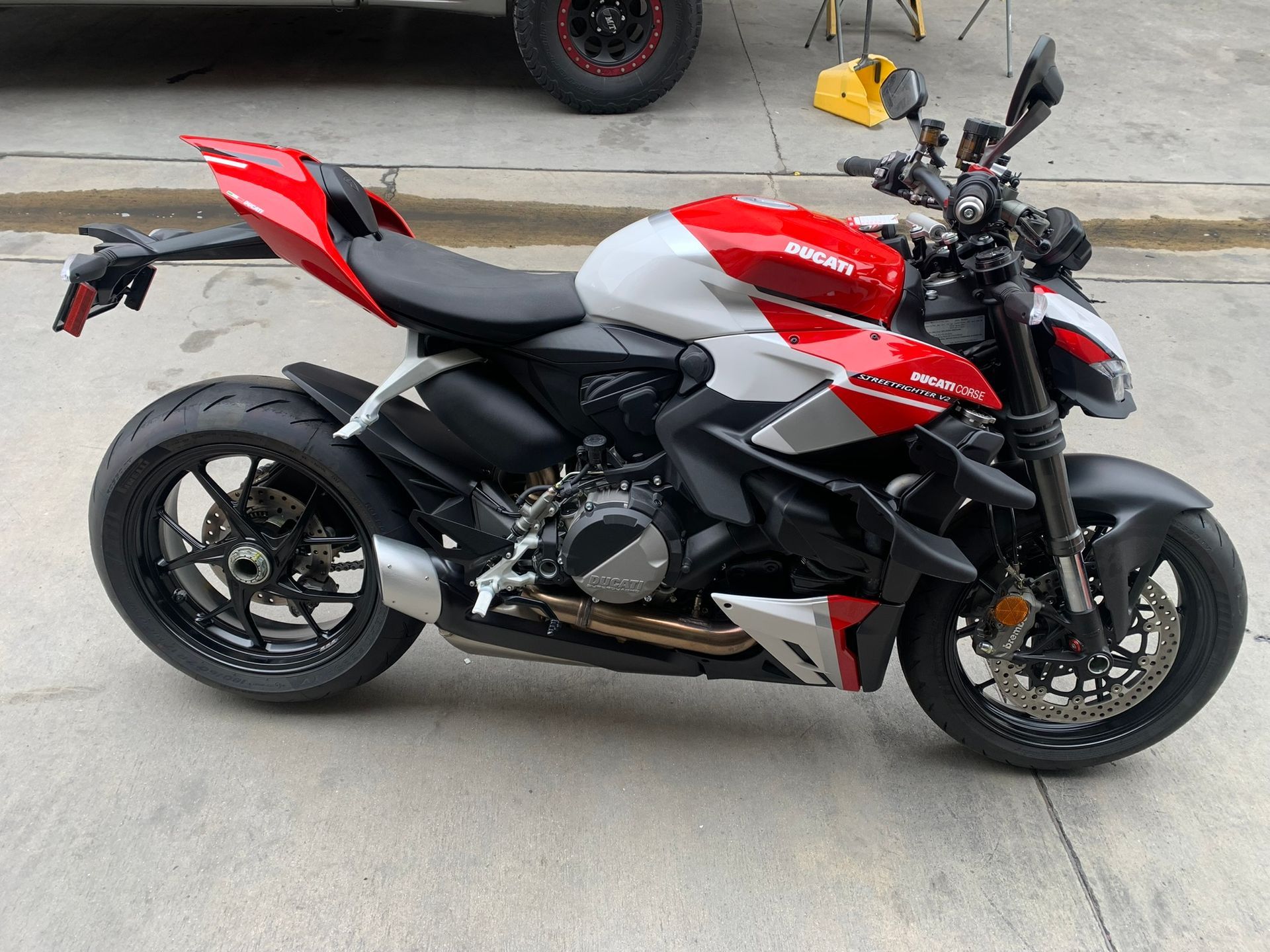 Red, black, and silver sport motorcycle parked on pavement, side view.