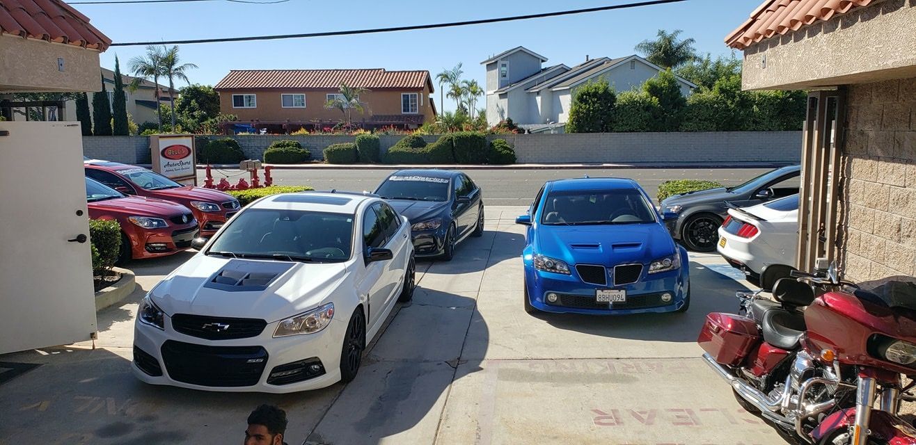 Parking lot with several parked cars, including a white SUV and a blue sedan, beside buildings.