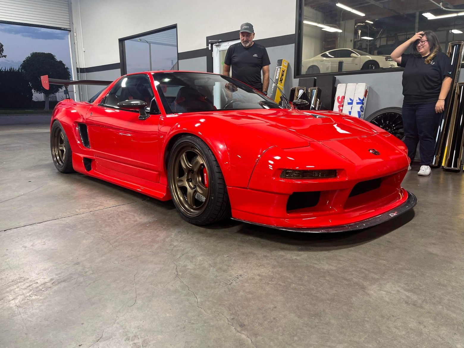 Bright red sports car in a garage with two people standing nearby