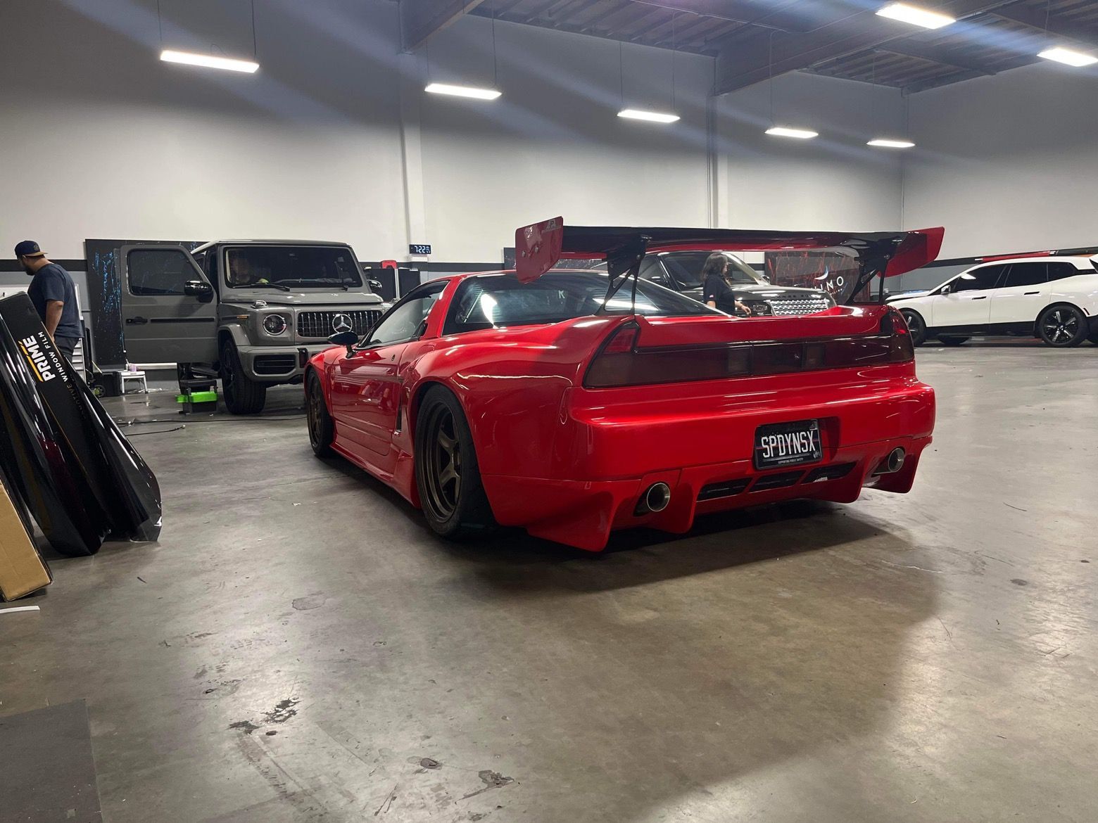 Red sports car in a garage with several vehicles parked around it.