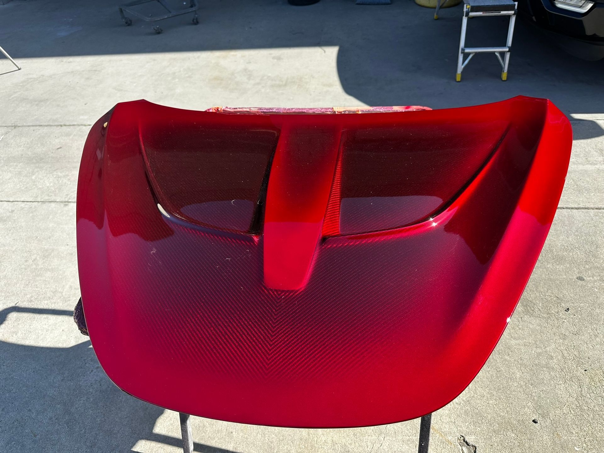 Red car front bumper with grille opening, shown outdoors on pavement.