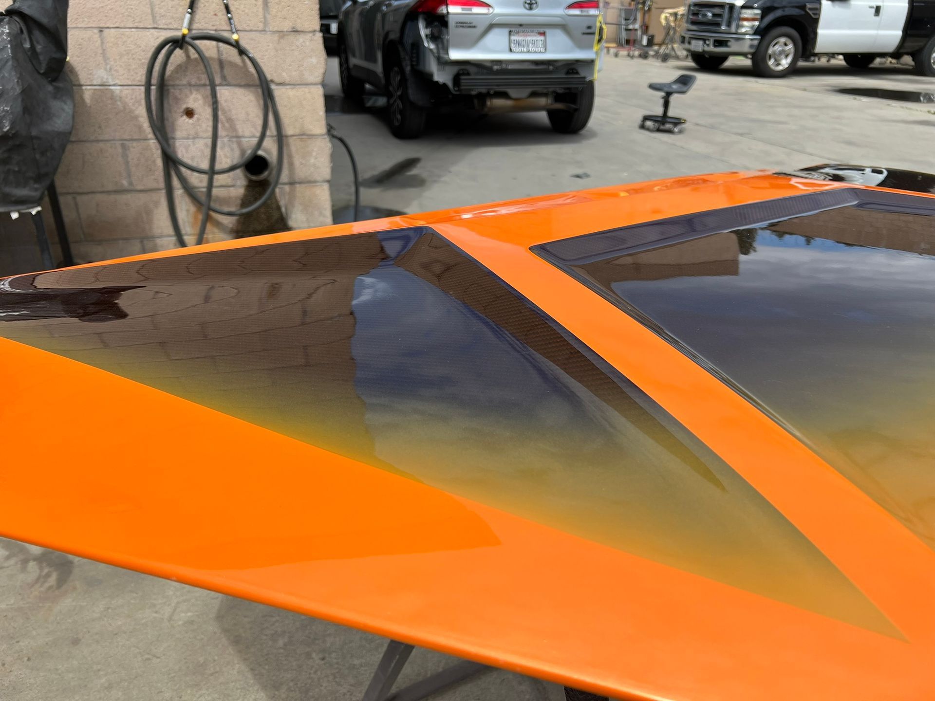 Orange sports car roof with dark tinted windows in a parking lot