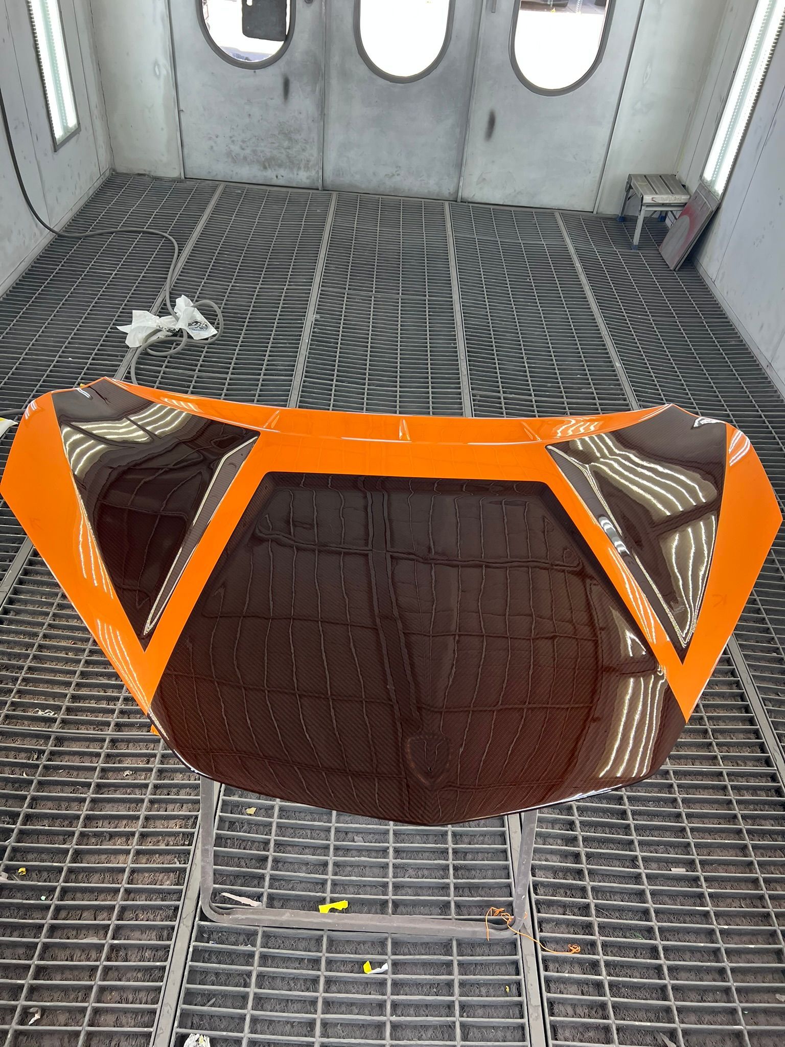 Orange-and-black industrial component on a grated metal floor inside a gray enclosure.