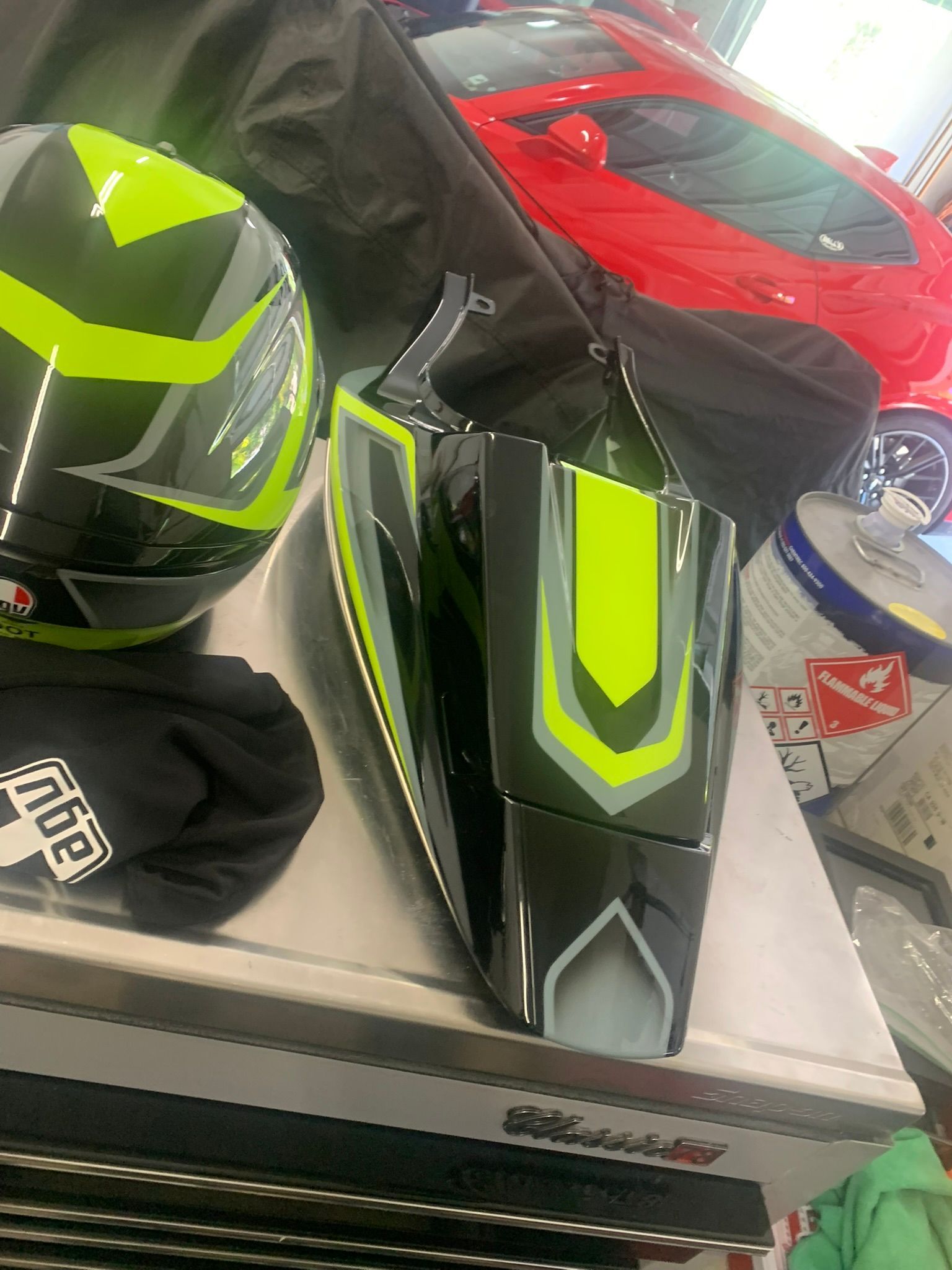 Two neon green and black bike fairings on a table, with a red vehicle body in the background.