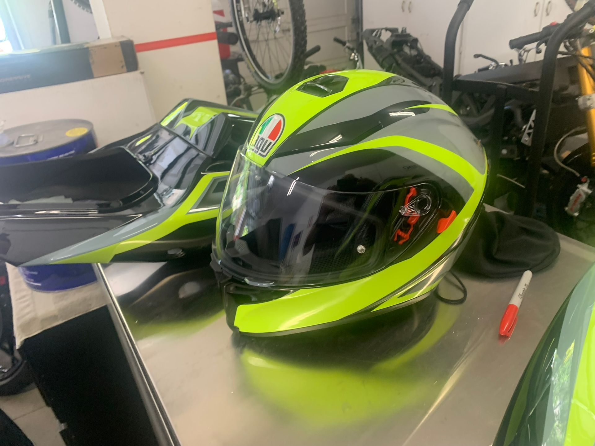 Neon yellow and black racing helmet on a workbench beside motorcycle gear and tools.