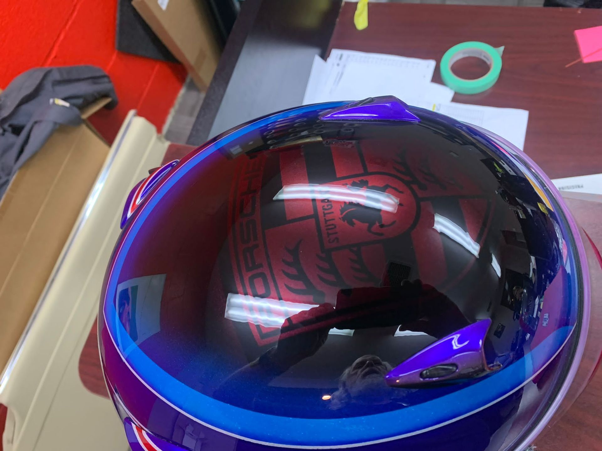 Glossy black helmet with blue and purple accents on a table in a workshop