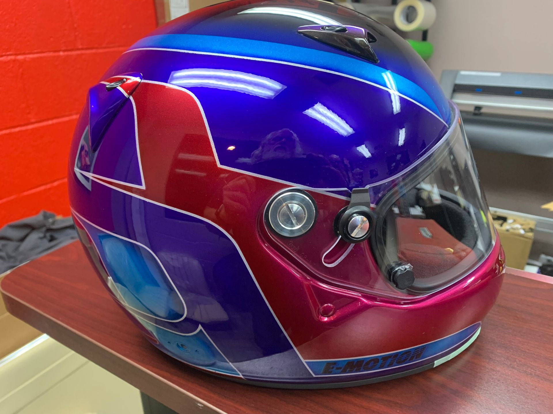 Purple and red full-face motorcycle helmet with a reflective visor on a table