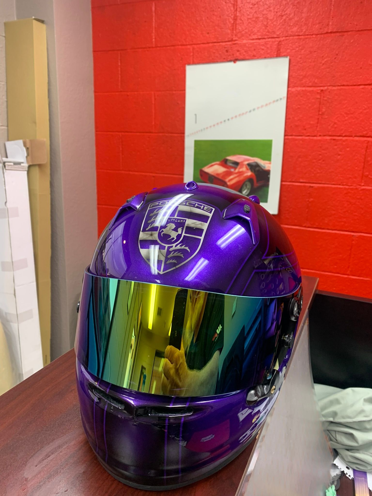Purple motorcycle helmet with mirrored visor on a table against a red wall