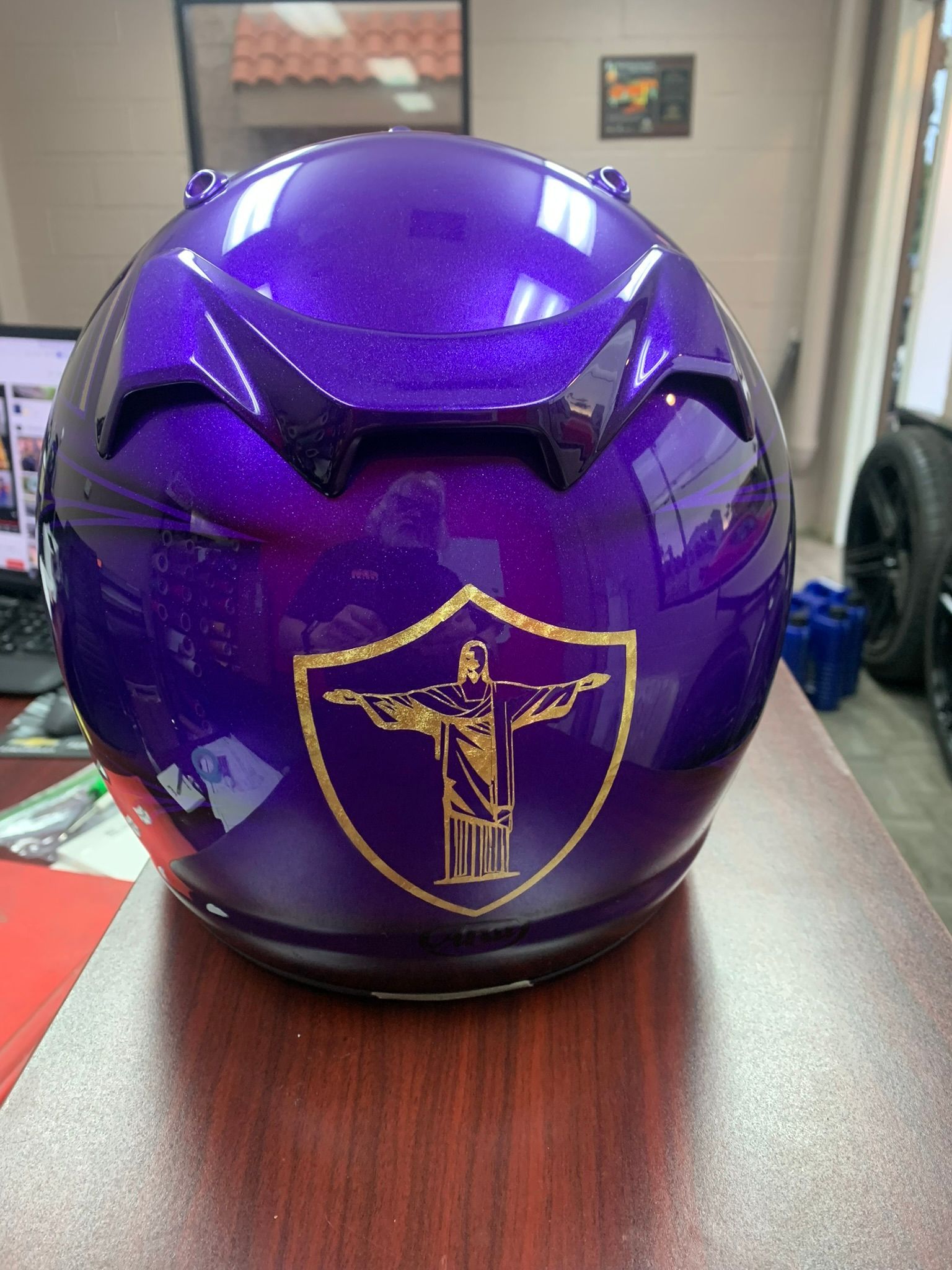 Purple helmet with gold crest logo on a desk in an office setting