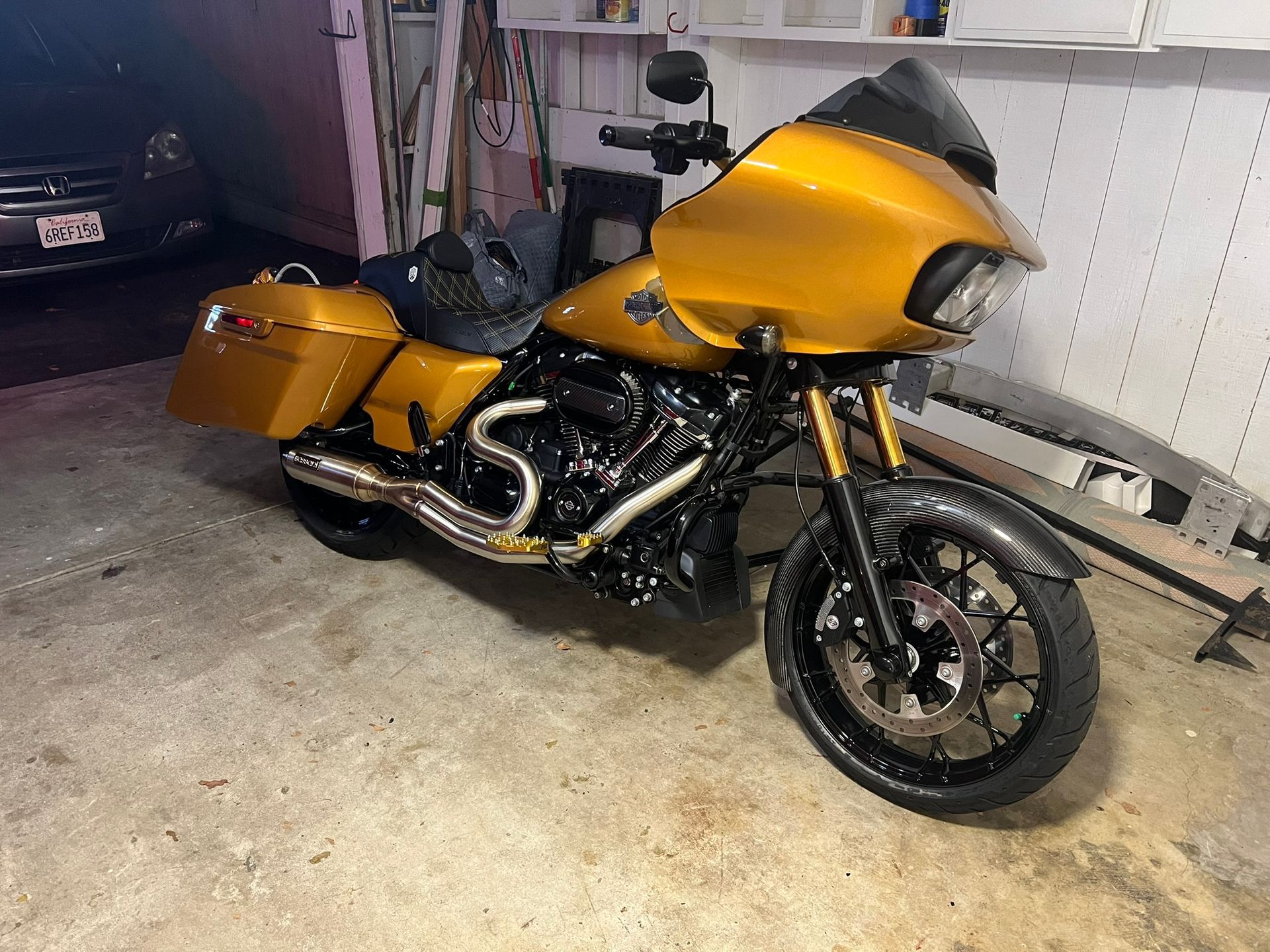 Yellow touring motorcycle parked in a garage, with matching saddlebags and black wheels.