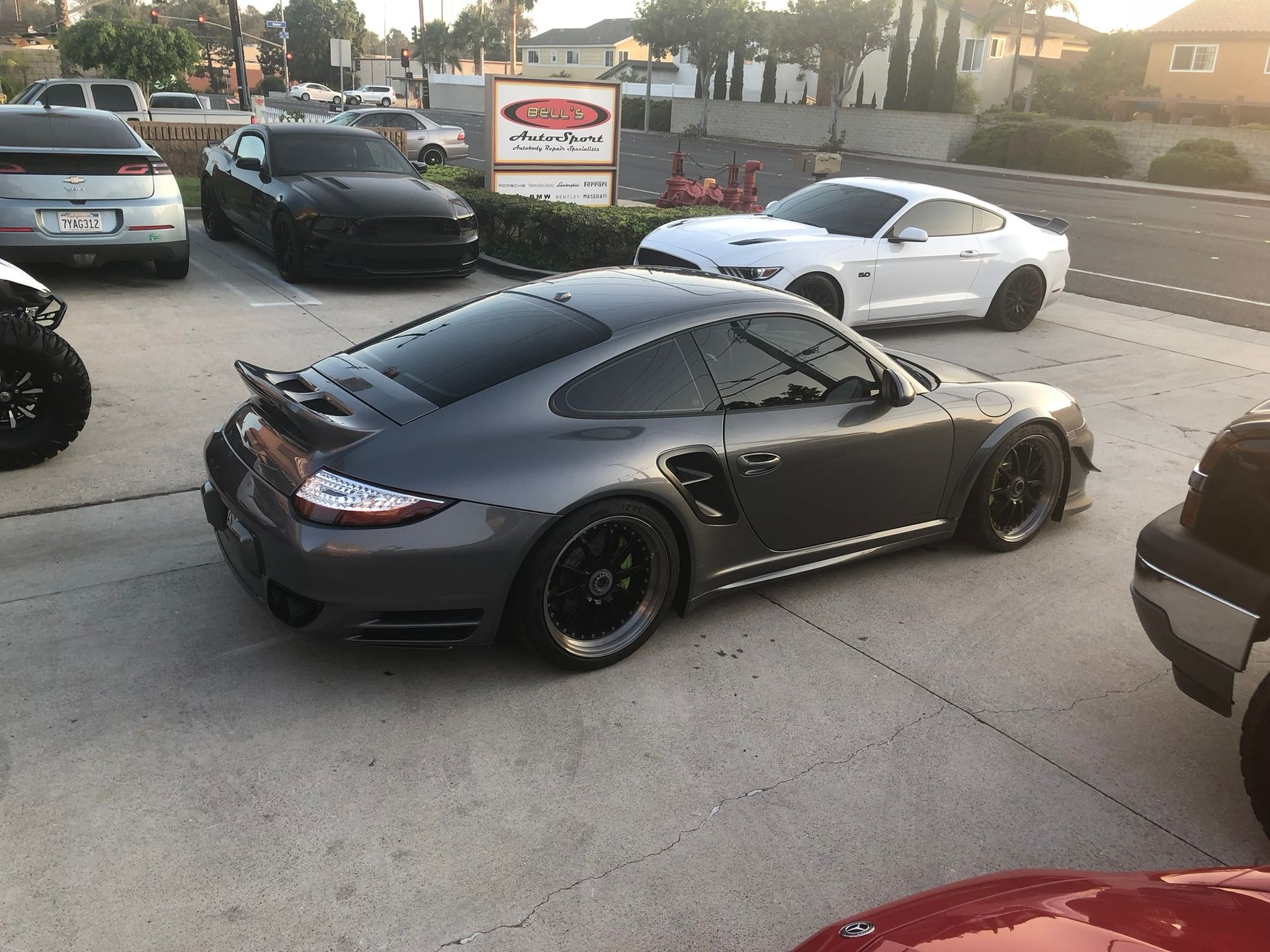 Black sports car parked in a lot beside a white coupe at sunset