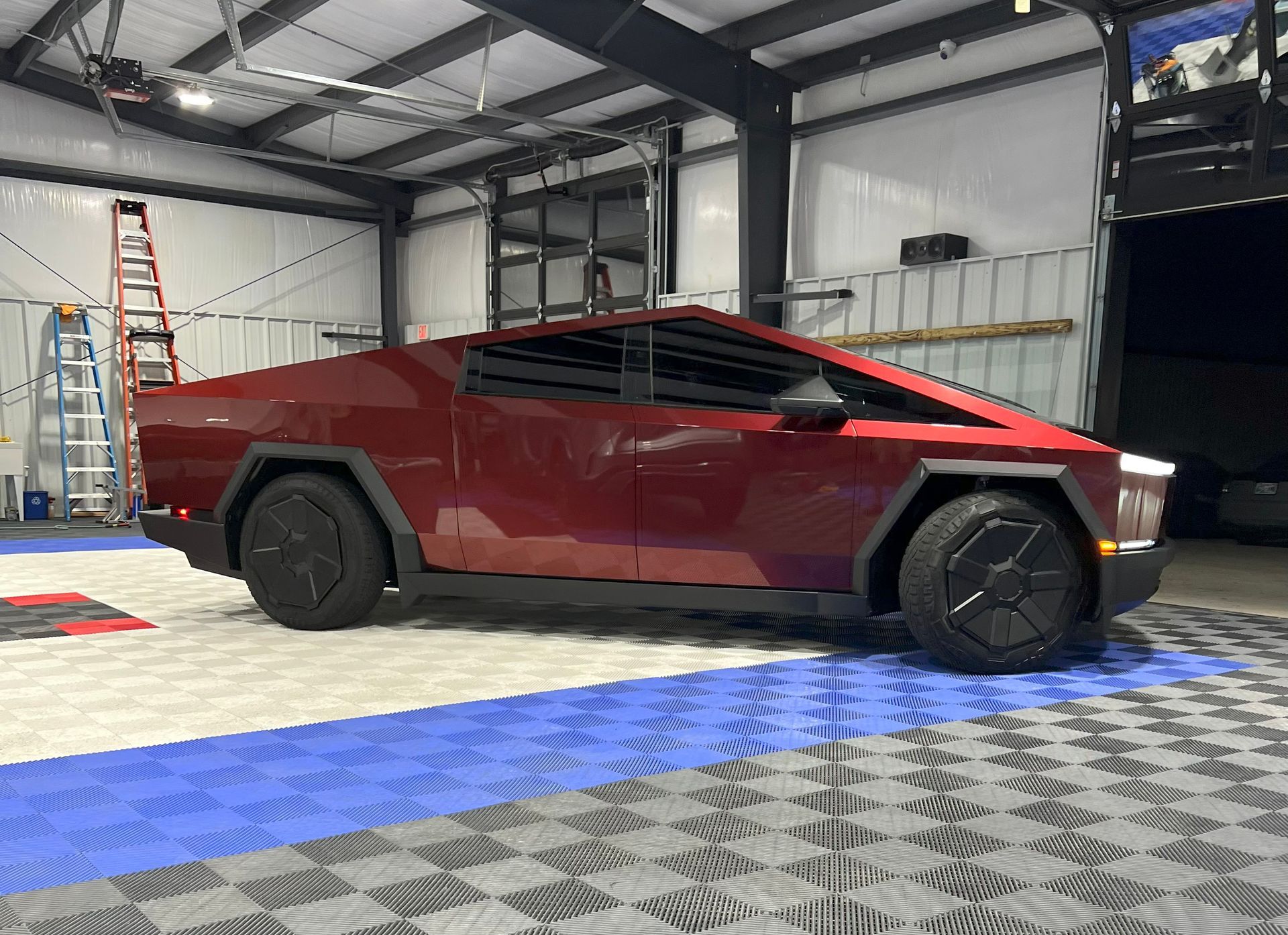 Red Tesla Cybertruck in a garage with black wheels.
