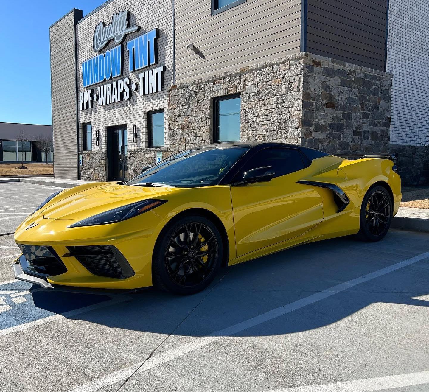 Yellow Corvette parked in front of a business with a sign that reads 
