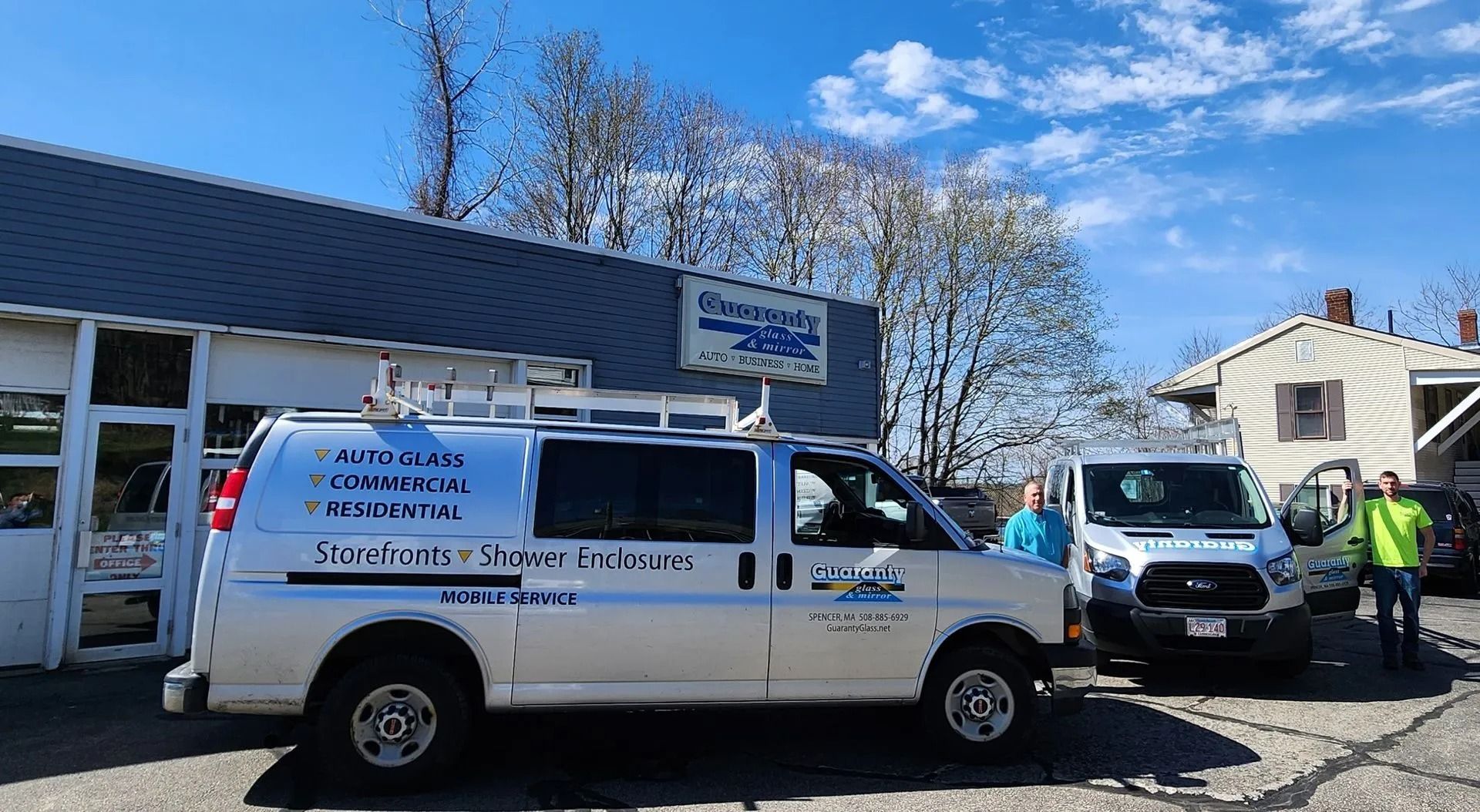 Two service vans parked outside a business under a blue sky. One has text: 