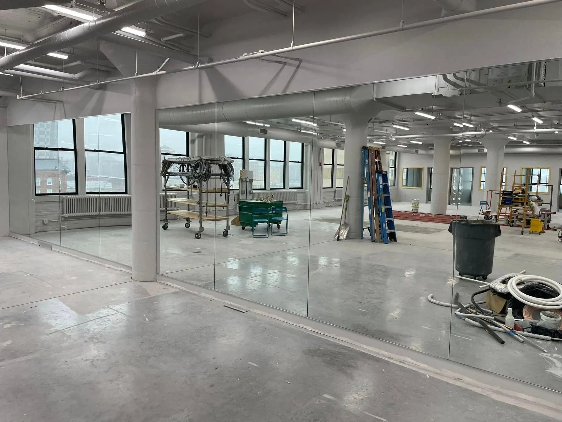 Interior of a modern unfinished office space with windows, columns, and construction materials scattered around.