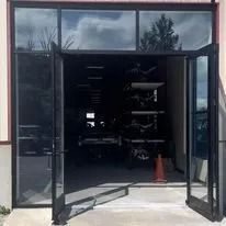 Glass doors of a building, open, revealing dark interior with equipment.