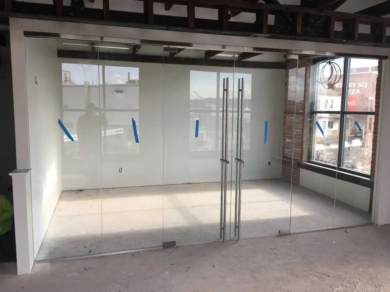 Glass office space under construction, with glass doors and walls. Light and open space, unfinished.