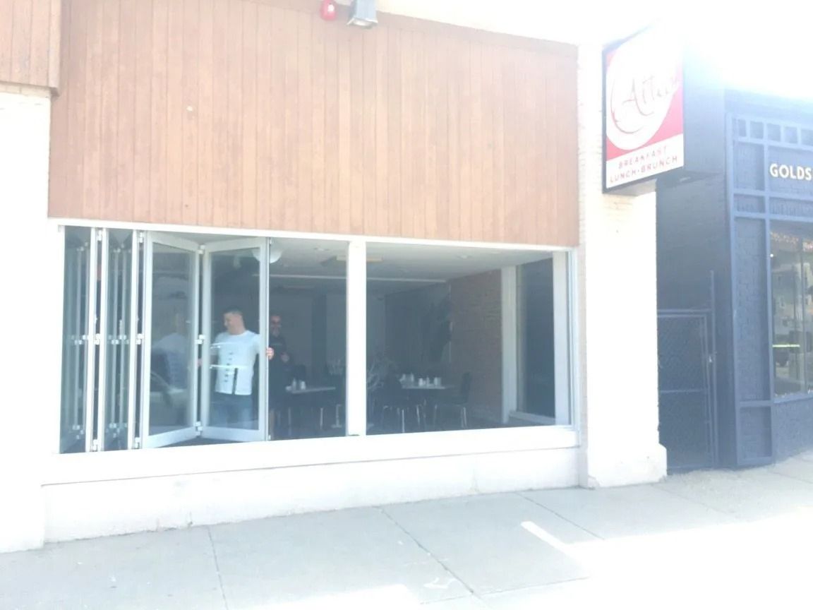 Restaurant exterior with open windows, a person visible inside, and signage on the right.