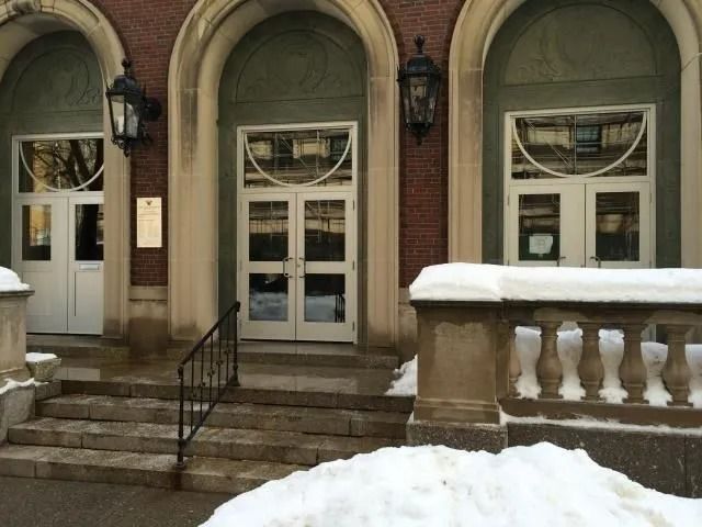Building entrance with arched doorways, snow-covered steps, and ornate lanterns.