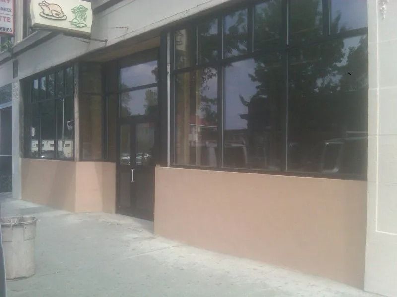 Restaurant exterior with large windows, tan wall base, and sign showing a roasted bird.