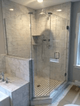 Modern bathroom with marble walls and a glass-enclosed shower featuring a tiled floor and built-in shelf.