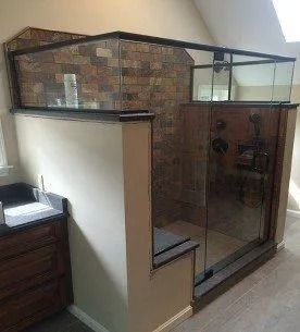 Walk-in shower with stone accent wall and glass panels, next to a vanity.