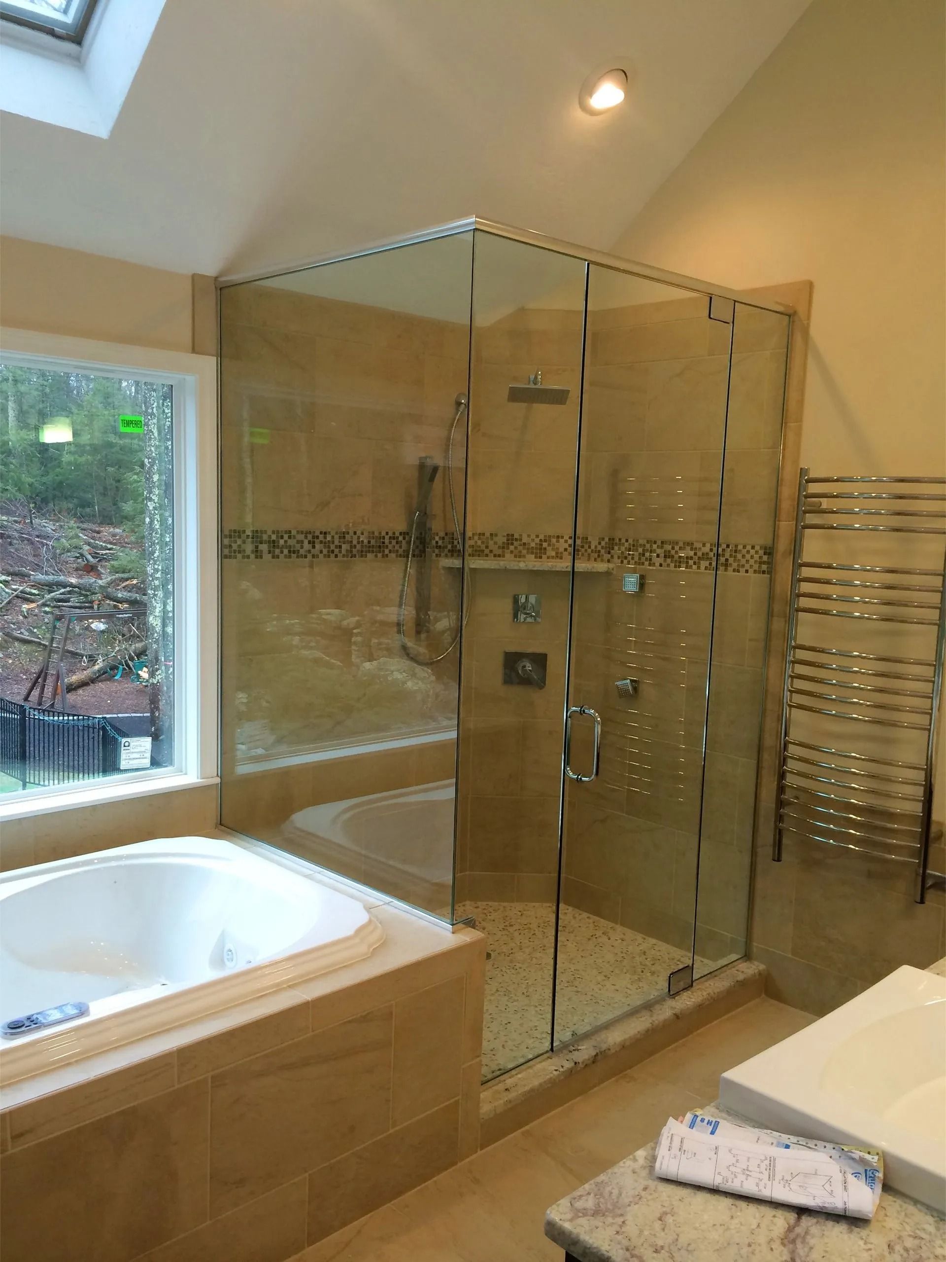 Bathroom with a glass shower, built-in tub, and tiled walls.