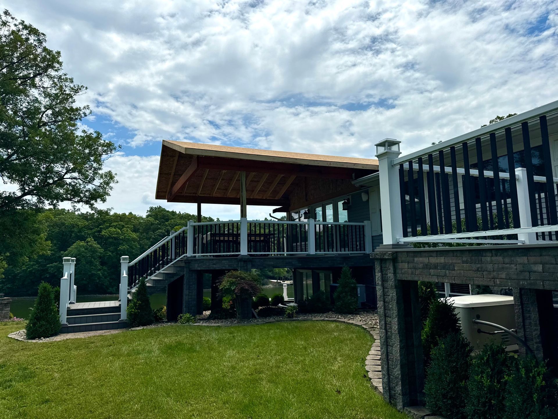 Lakefront deck with a brown roof and white railing, on a sunny day.