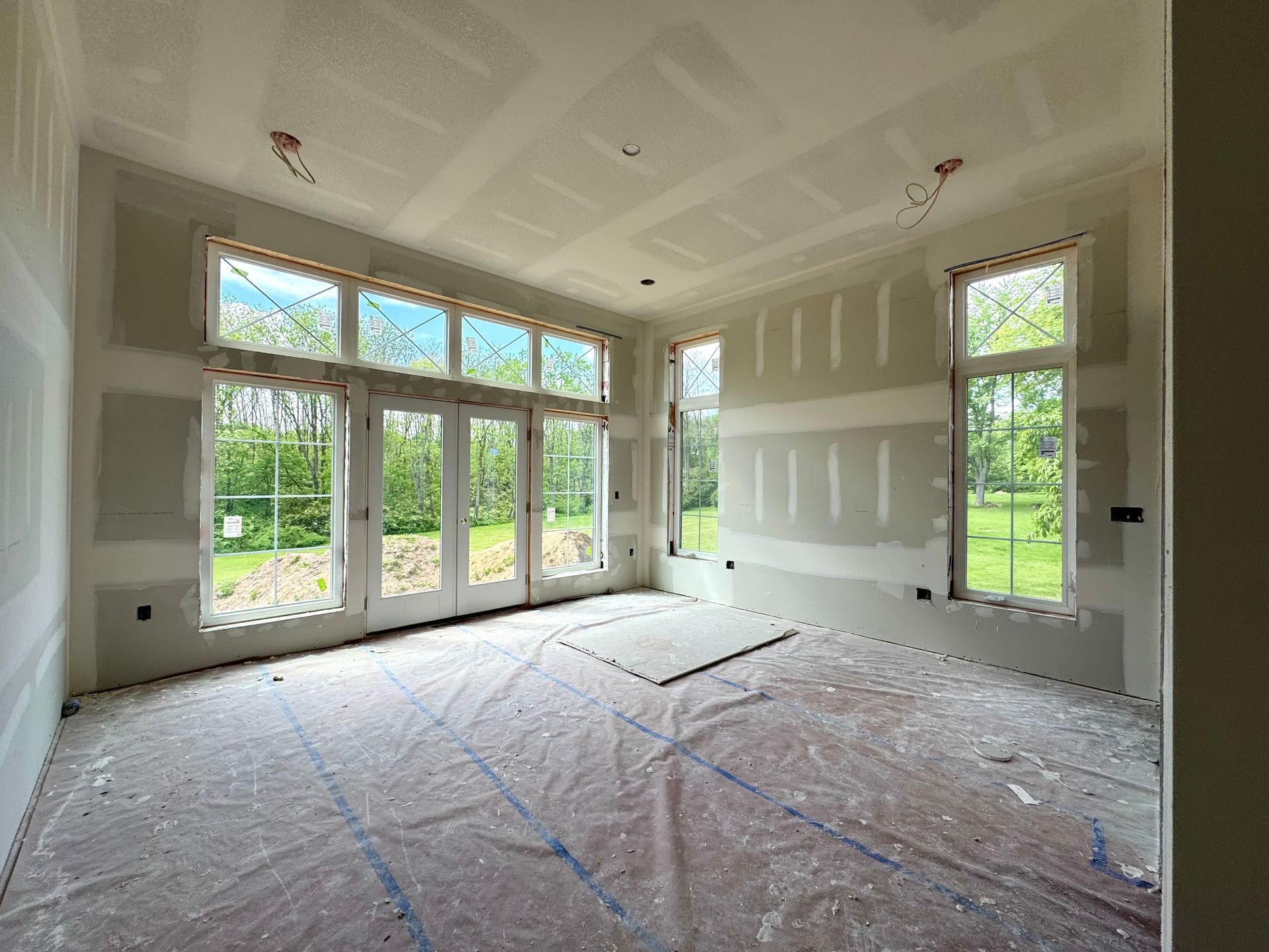 Unfinished room with drywall, windows, and patio doors; construction in progress.