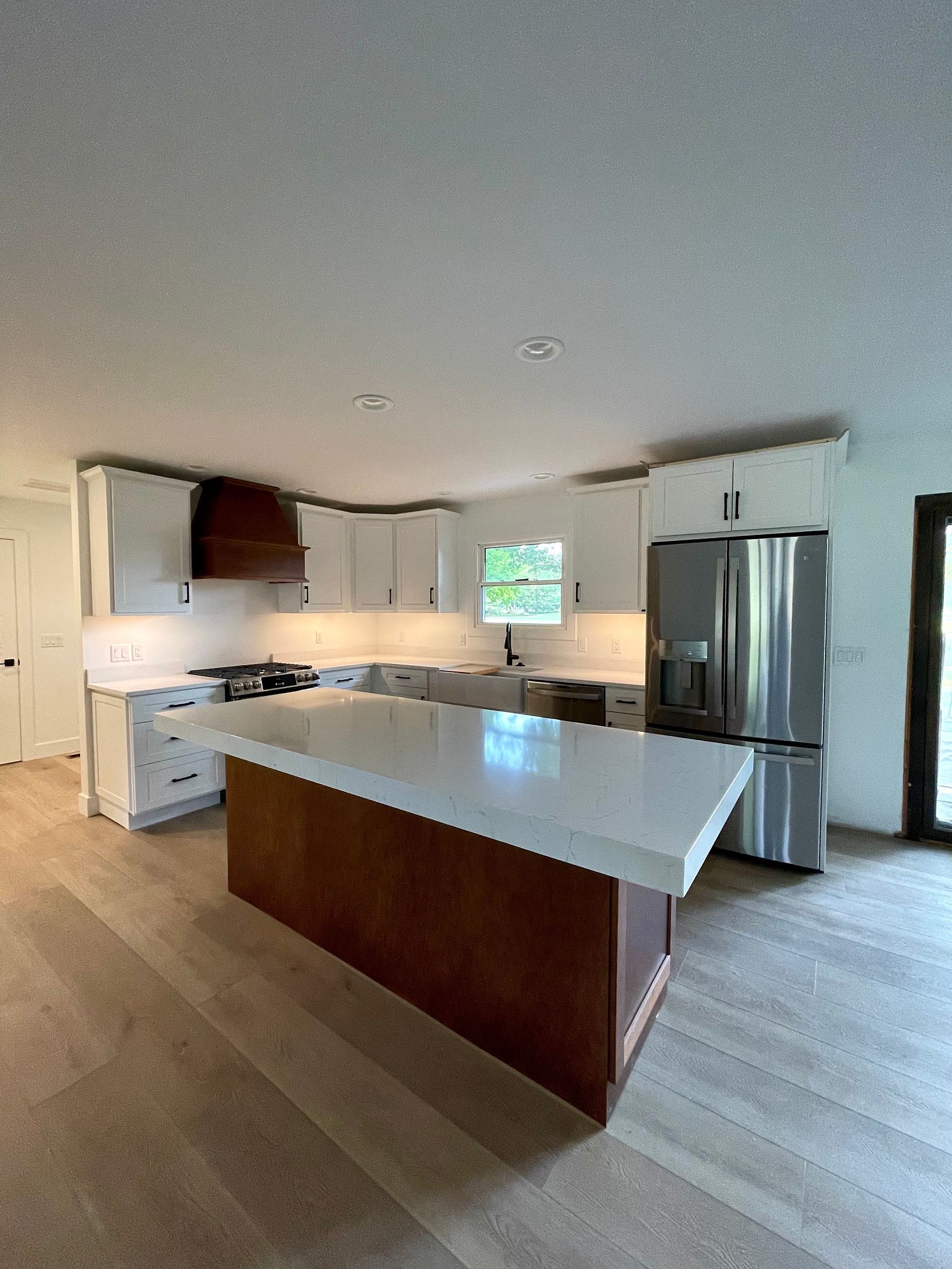 Modern kitchen with white cabinets, wood island, and stainless steel refrigerator.