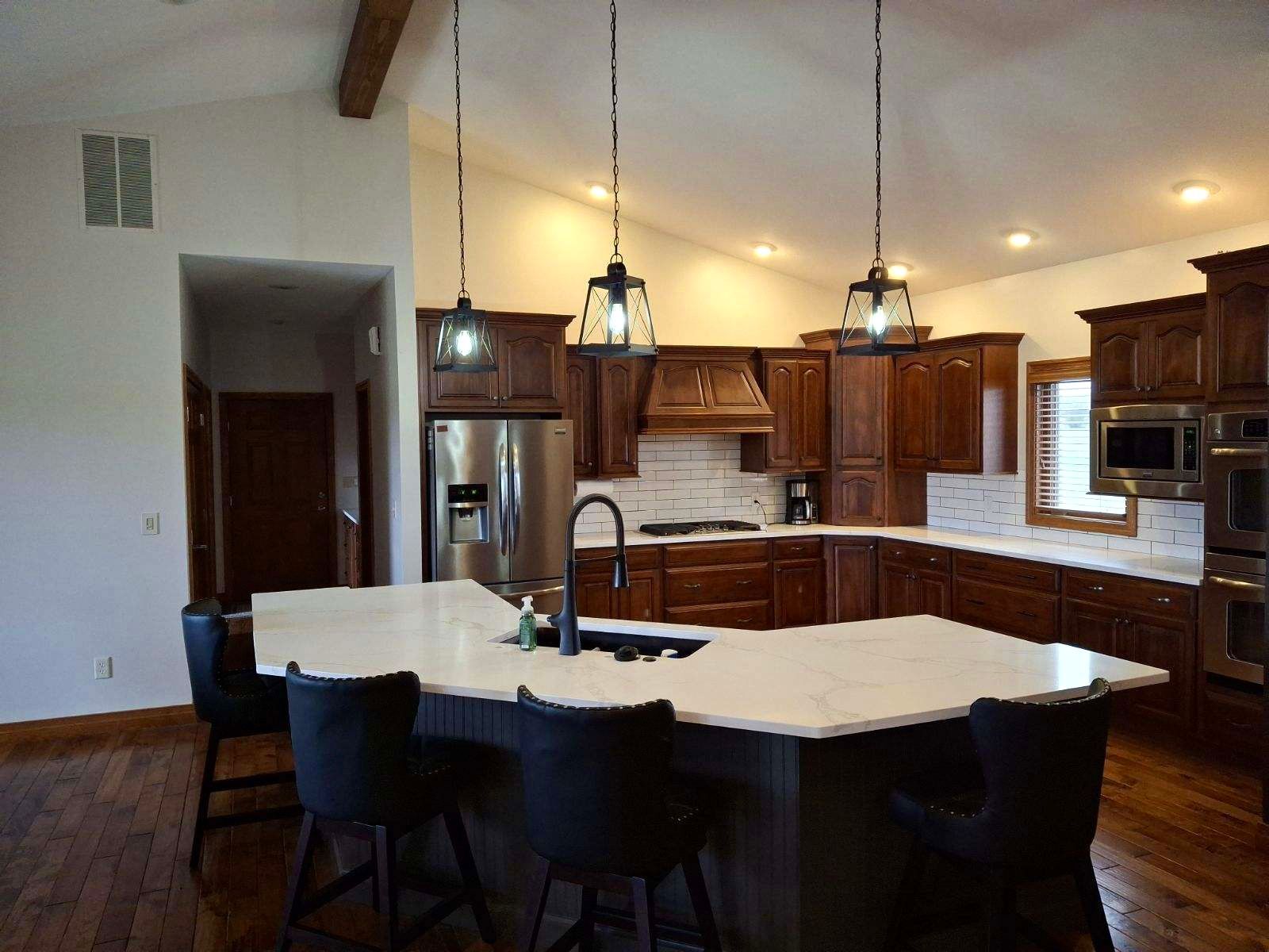 Kitchen with dark wood cabinets, white countertops, and pendant lights.
