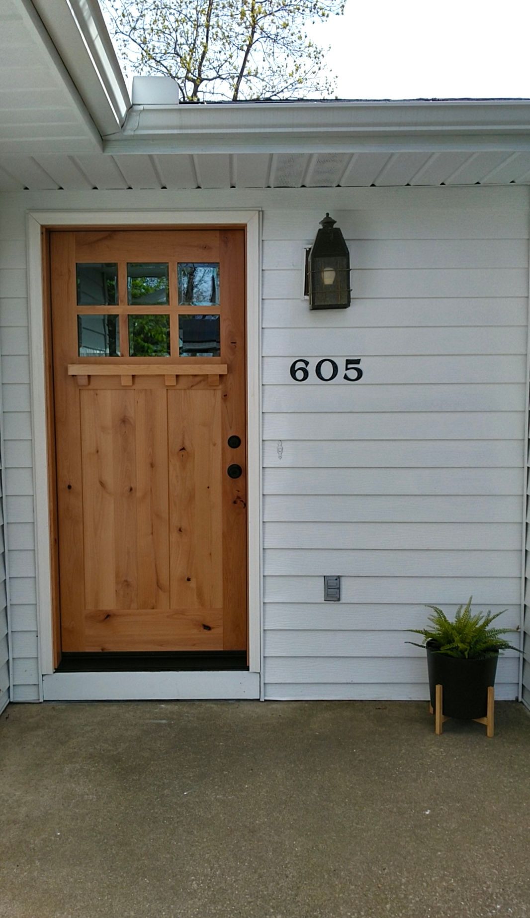 Wooden front door with glass panels and a black address number 