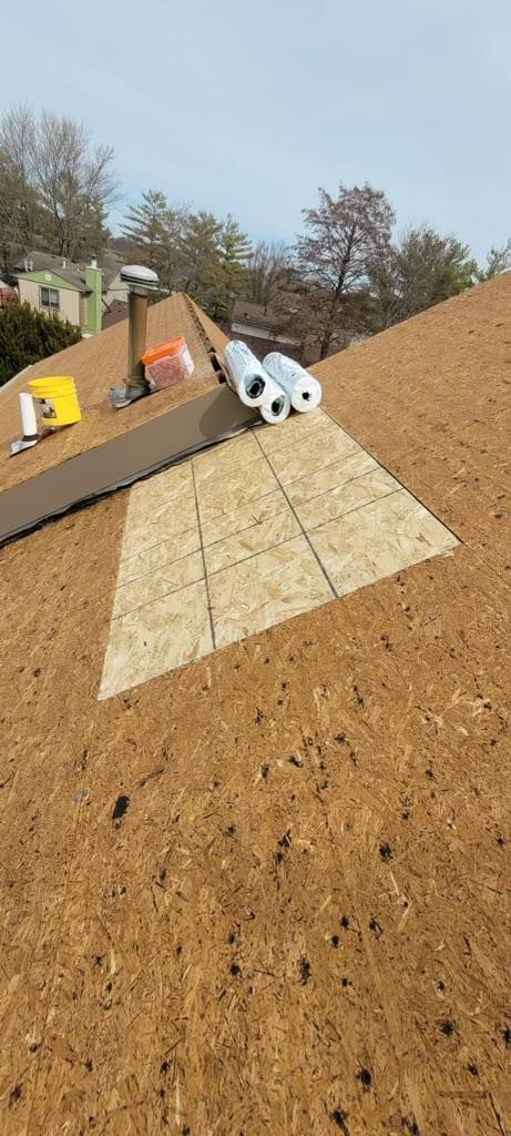 Roof under repair, materials on the roof with trees and sky in the background.