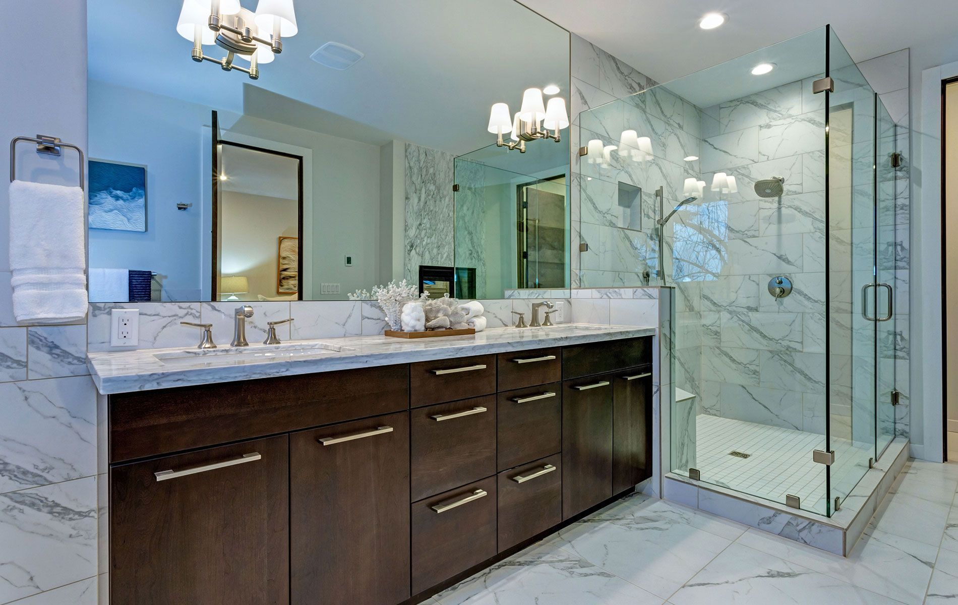Luxurious bathroom with marble surfaces, dark wood vanity, and glass shower.