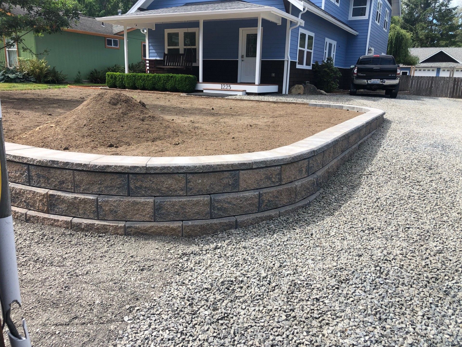 A blue house with a gravel driveway in front of it.
