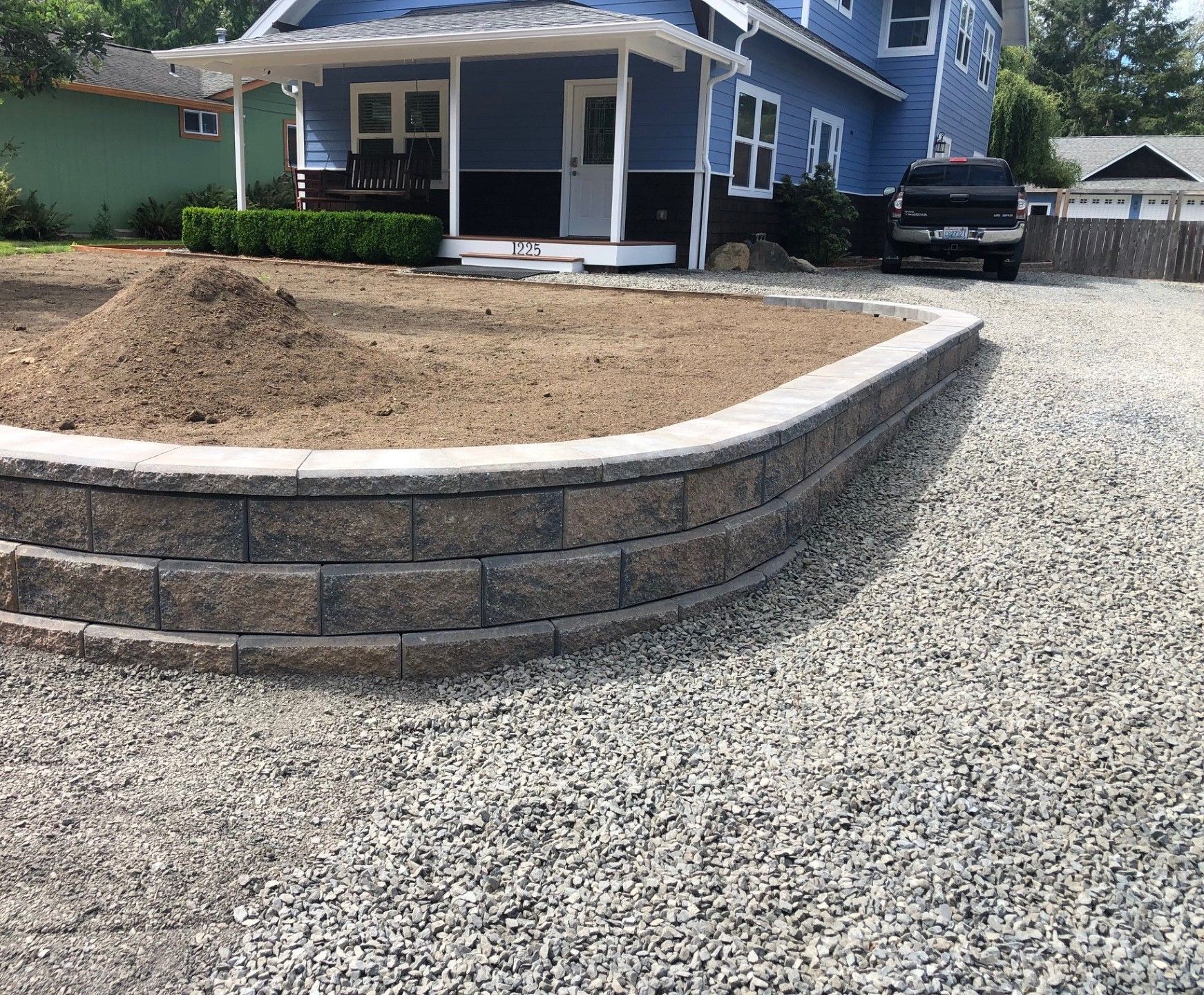 A blue house with a gravel driveway in front of it.