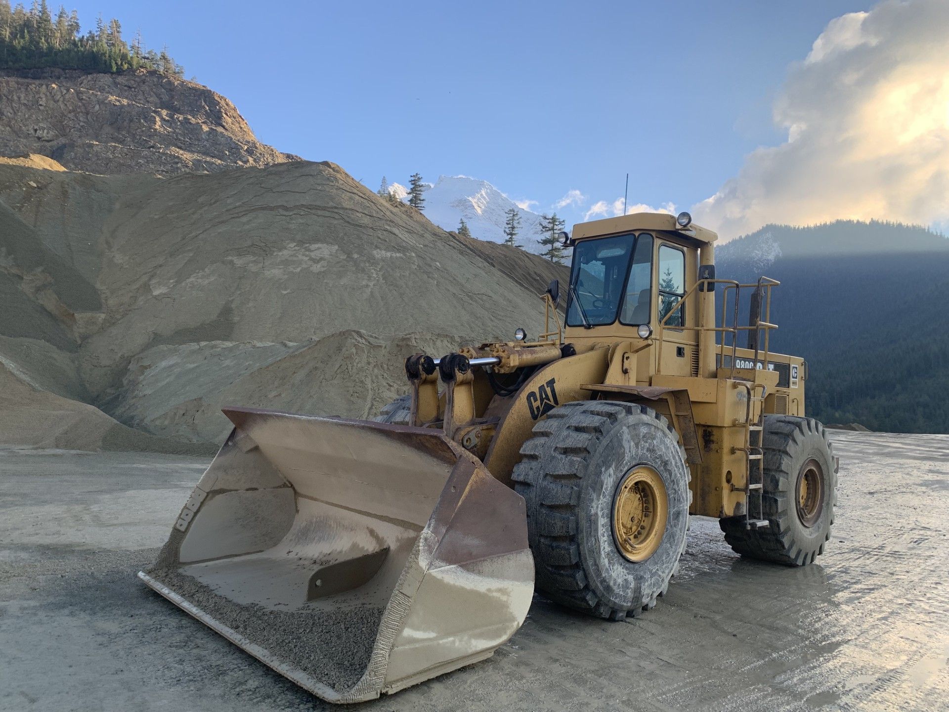 A bulldozer with a large bucket is parked in front of a mountain.