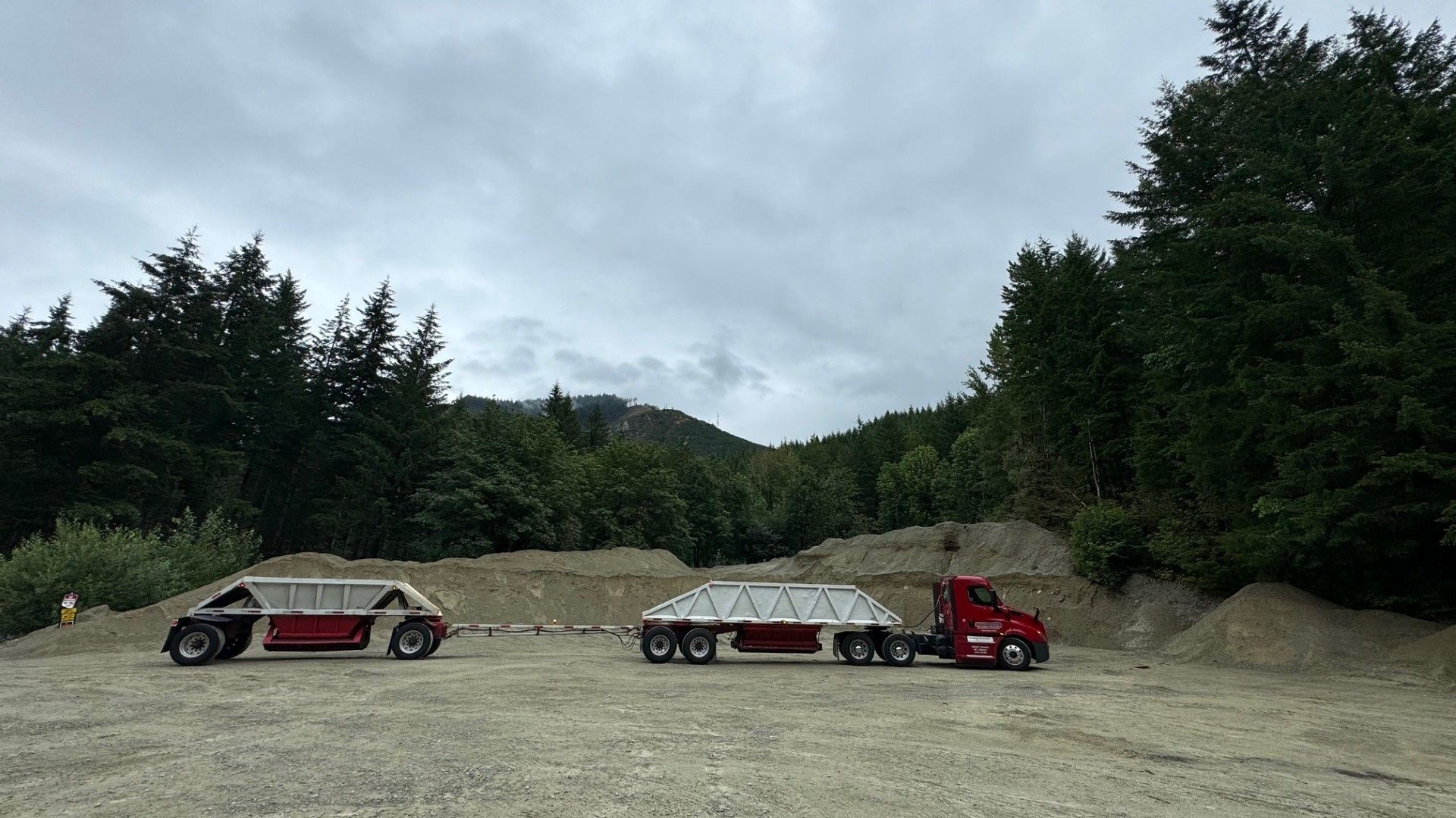 Two trucks are parked next to each other in a dirt field.