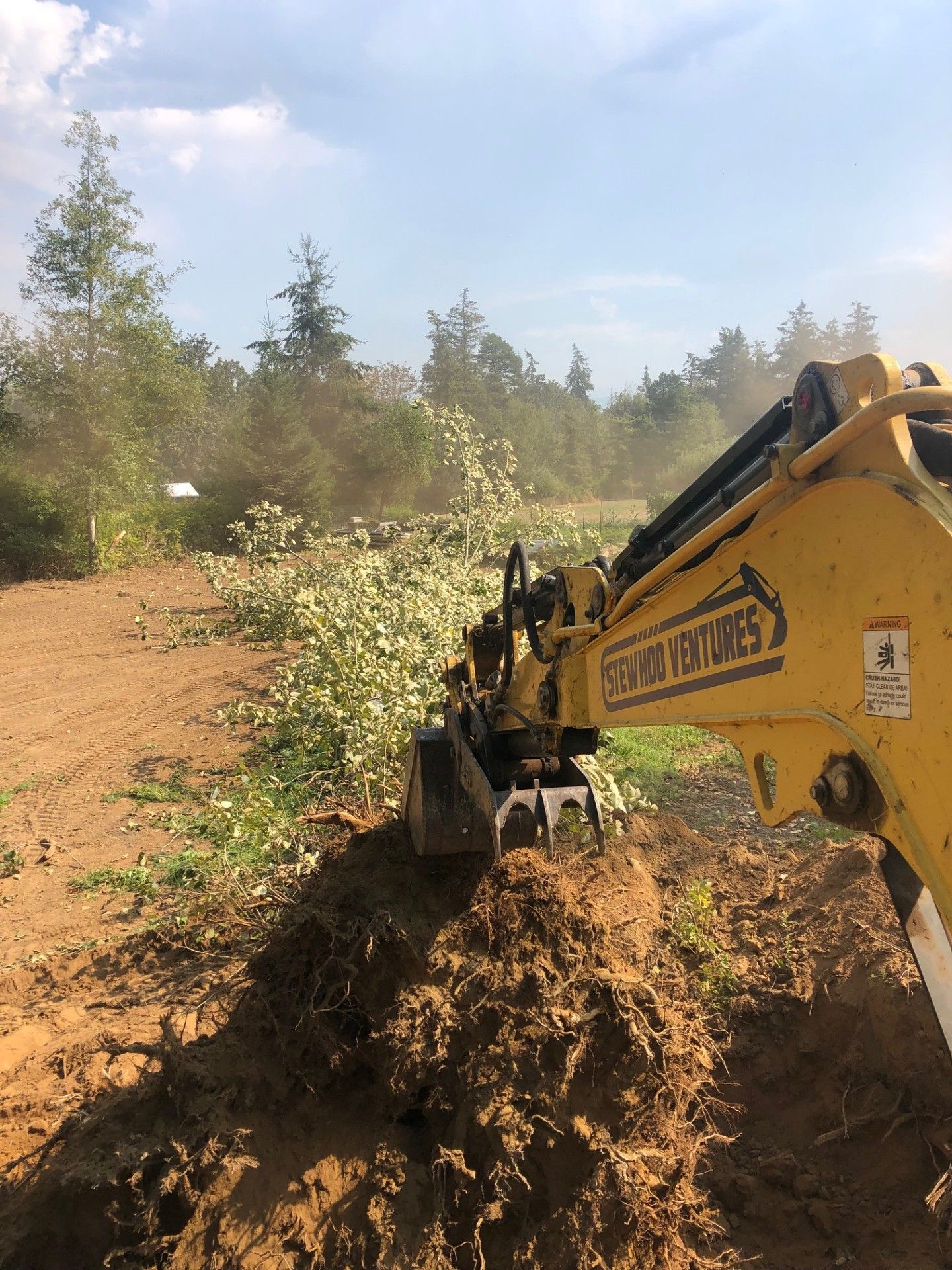A yellow excavator is digging a hole in the dirt in a field.