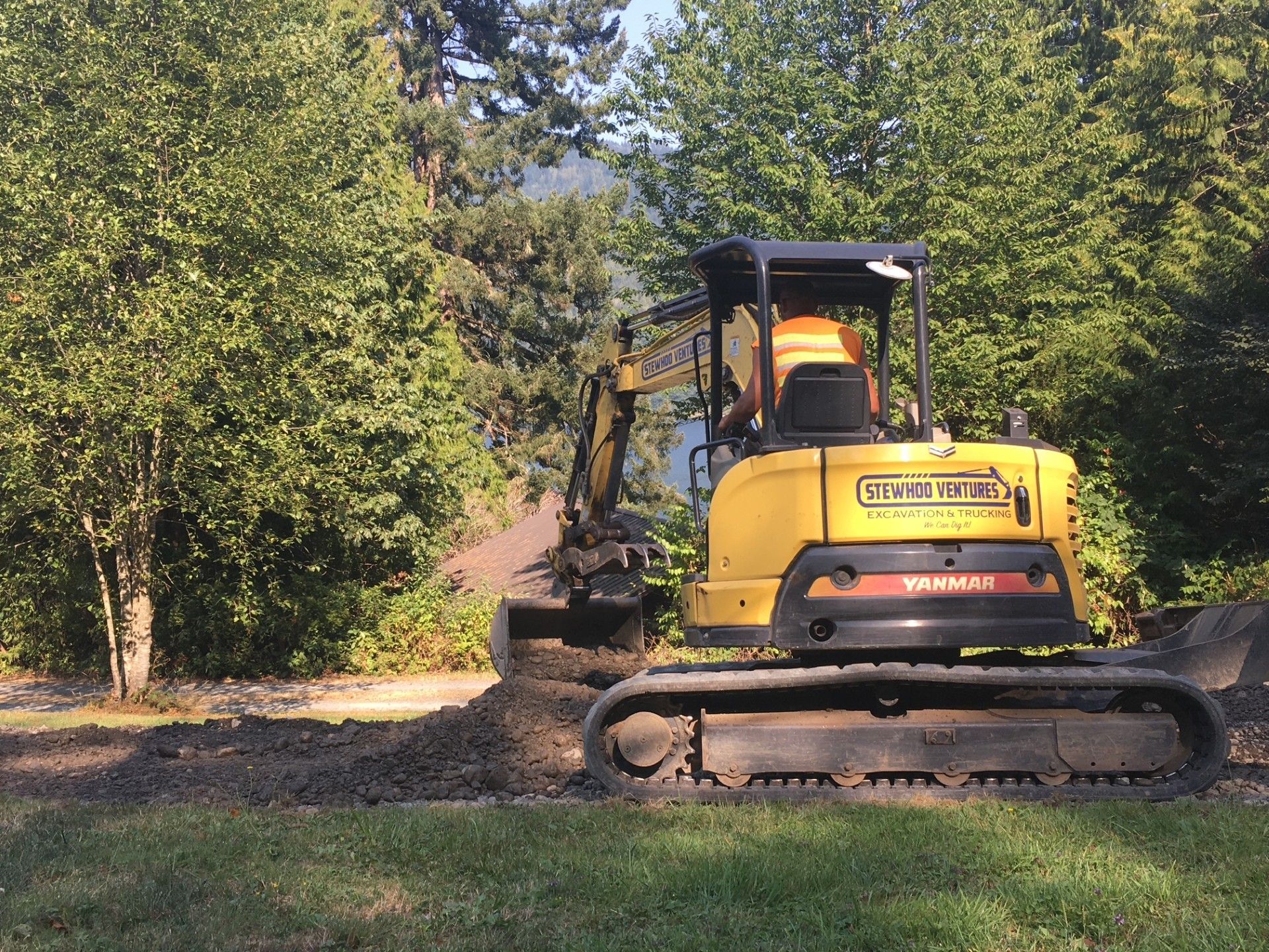 A yellow excavator is driving down a dirt road.
